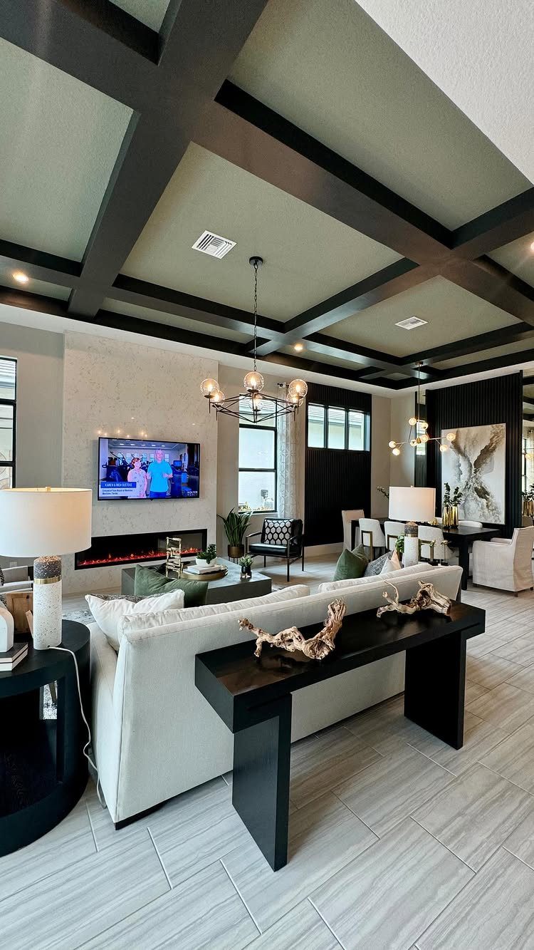 Modern open-concept living area with a white sofa, dark coffered ceiling, and a dining area.