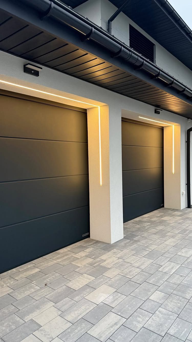 2 Car Garage Makeover Ideas: 8 Projects for a Finished Space 7 Two dark grey garage doors illuminated by bright LED light strips on a white exterior wall.
