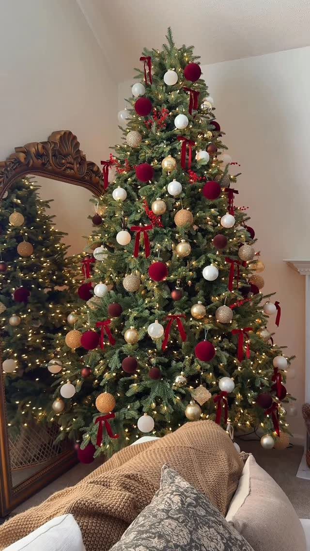 A decorated Christmas tree with red, gold, and white ornaments and warm lights.