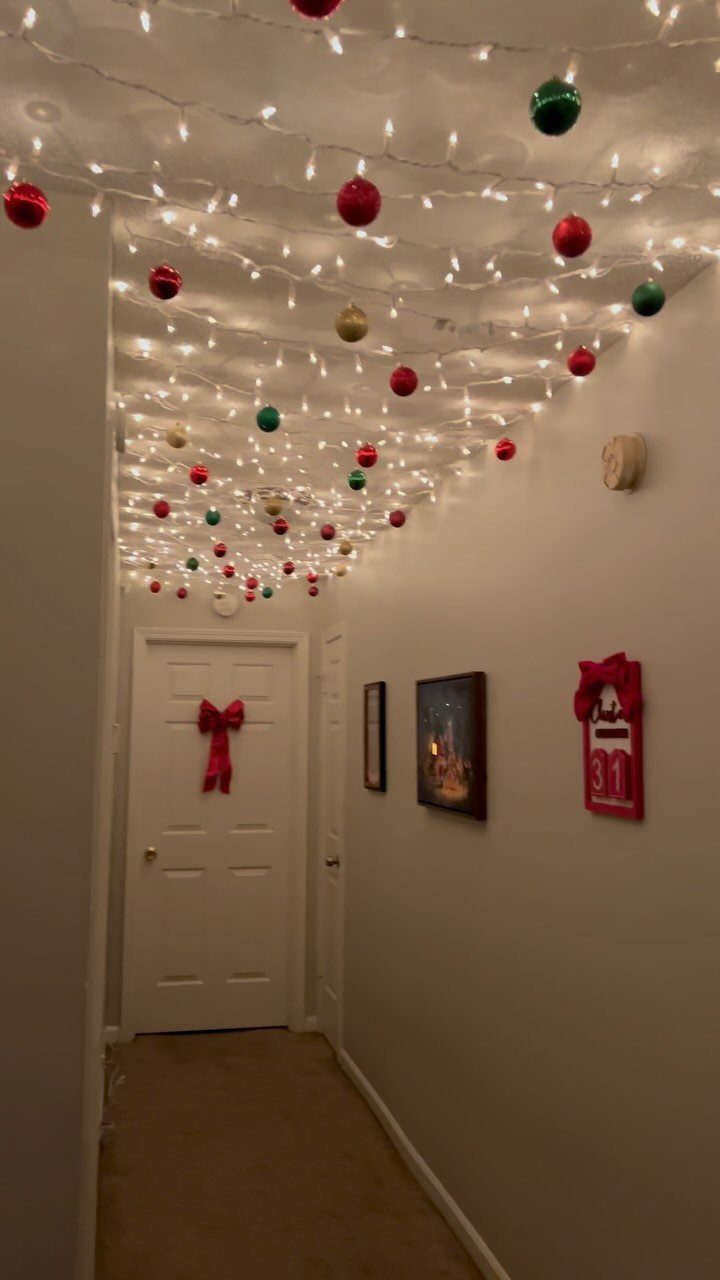 White string lights with colorful ornaments hanging from a hallway ceiling.