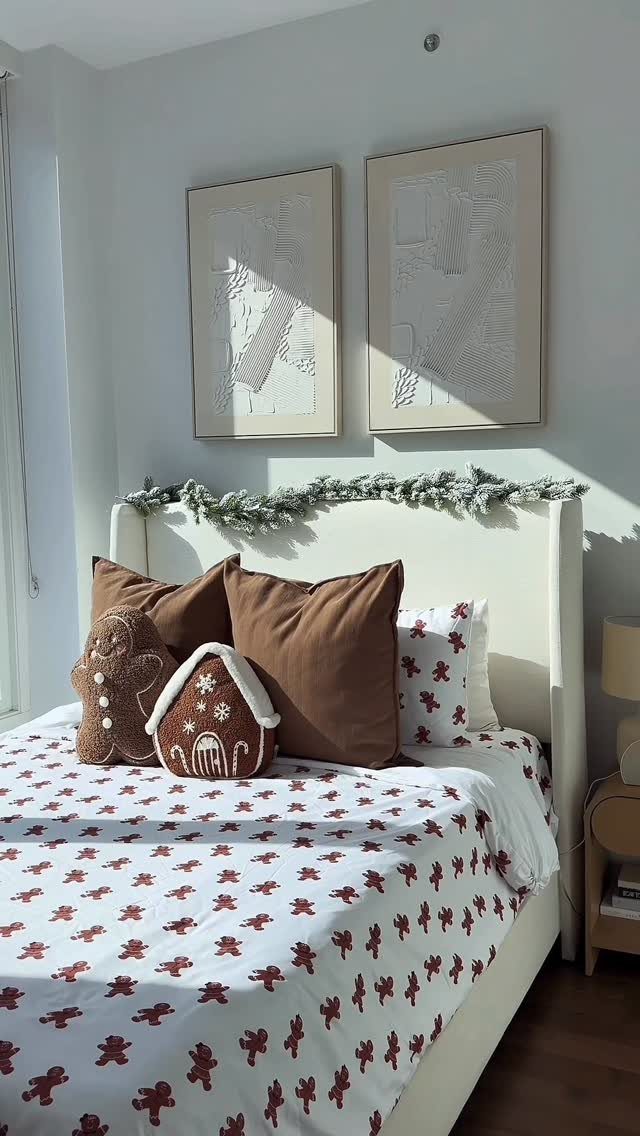 A bed decorated with gingerbread shaped pillows and a festive garland on the headboard.
