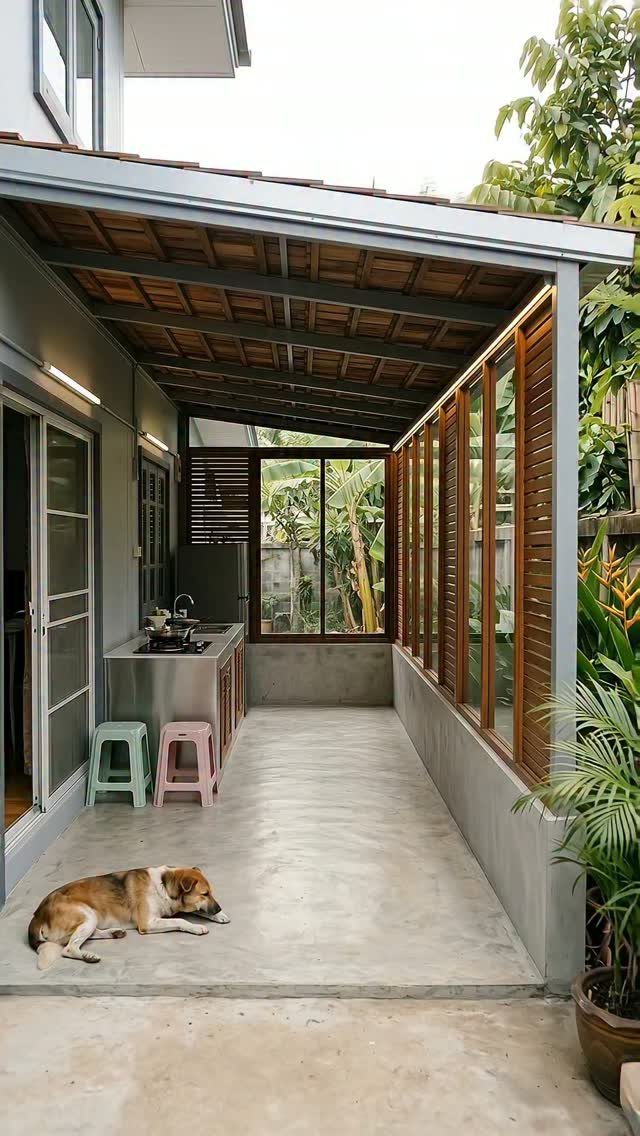 7 Back Porch Outdoor Kitchen Ideas for Covered Cooking 1 A dog lies on a concrete floor in a narrow covered patio with an outdoor kitchen.