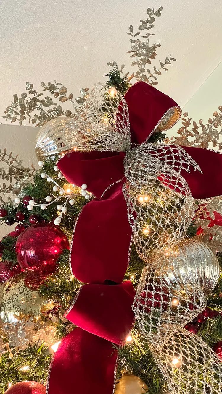 Christmas Bow Decor: 10 Ways to Use Them 2 A large red velvet and silver mesh multi-loop bow on a decorated Christmas tree.