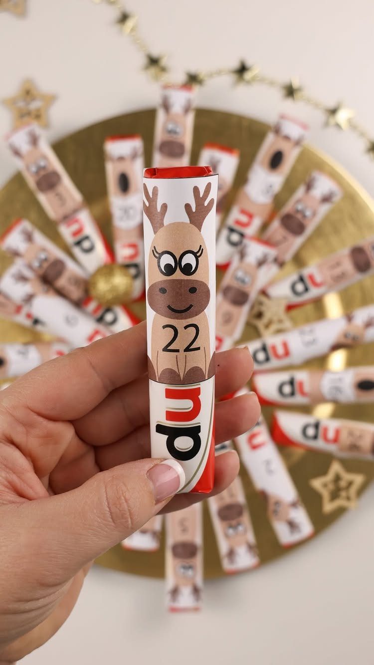 A hand holding a reindeer-themed paper tube numbered 22 from an advent calendar.