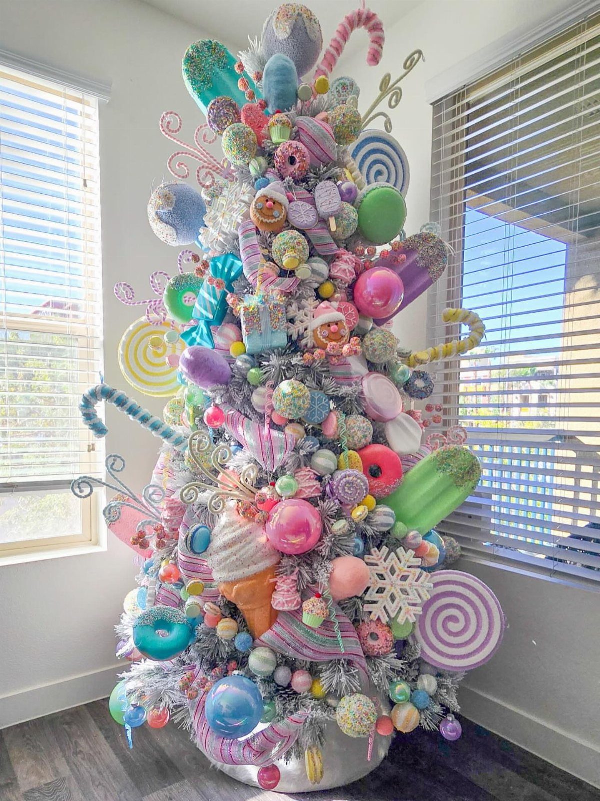 A whimsical Christmas tree decorated with oversized pastel candies, donuts, and lollipops.