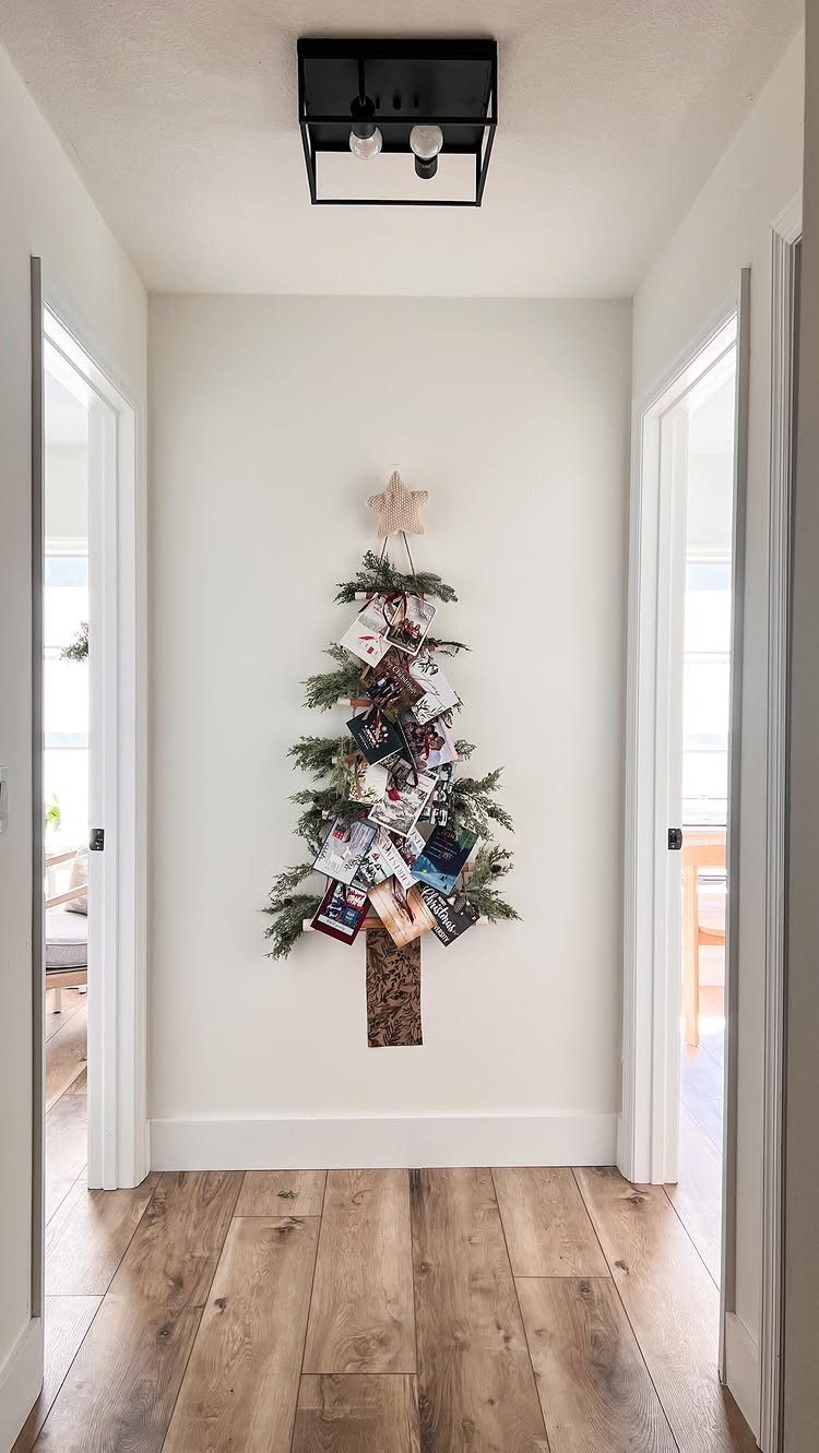 Christmas cards arranged in a tree shape on evergreen branches mounted on a white wall.