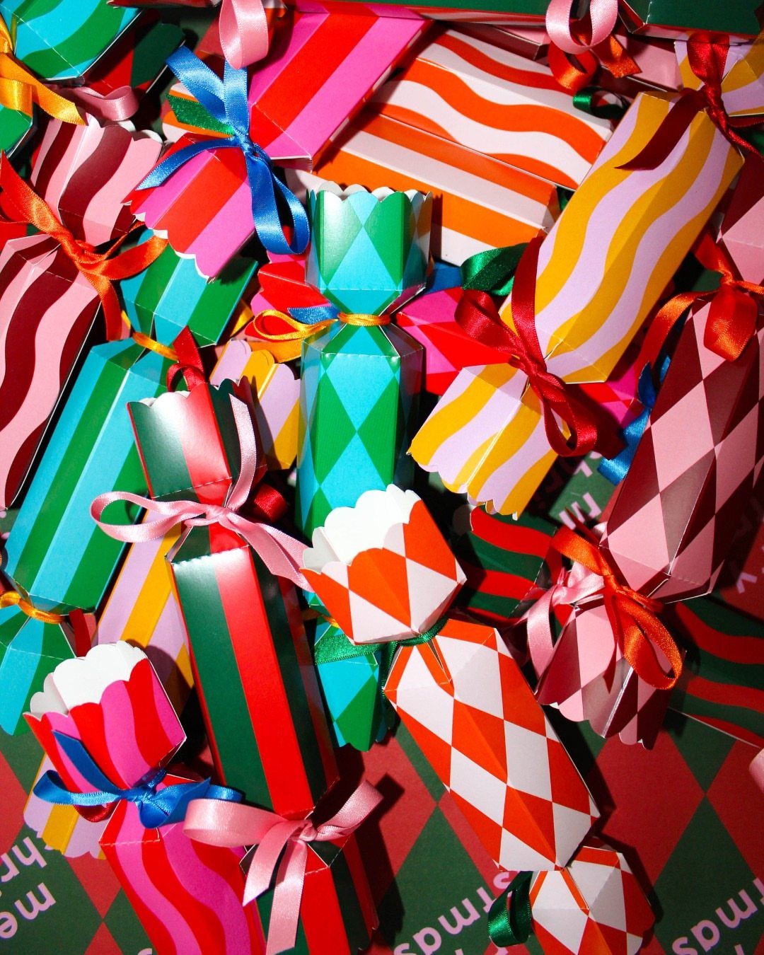 Colorful patterned Christmas crackers tied with satin ribbons piled together in a bright arrangement.