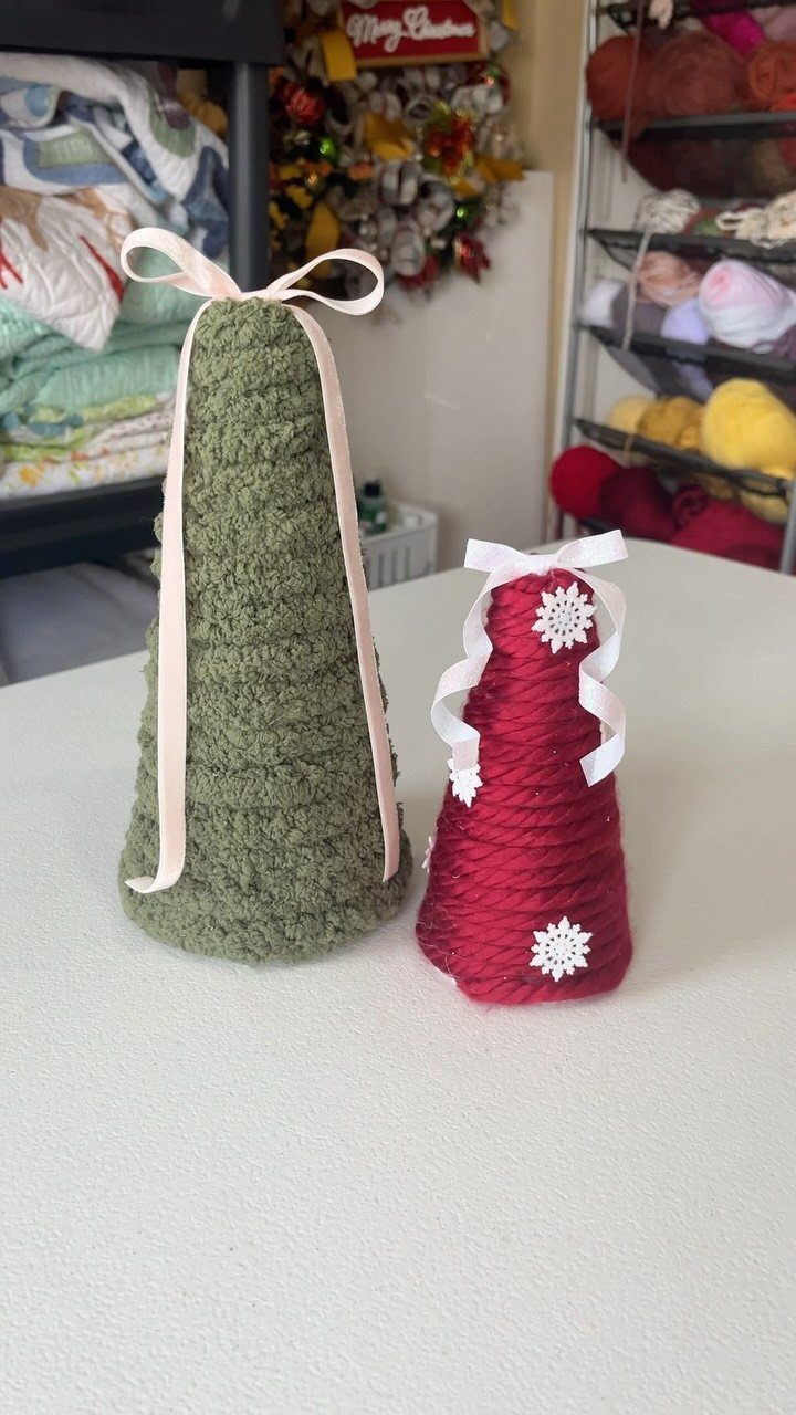 Two yarn cone trees, one large green and one small red, decorated with ribbons and snowflakes.