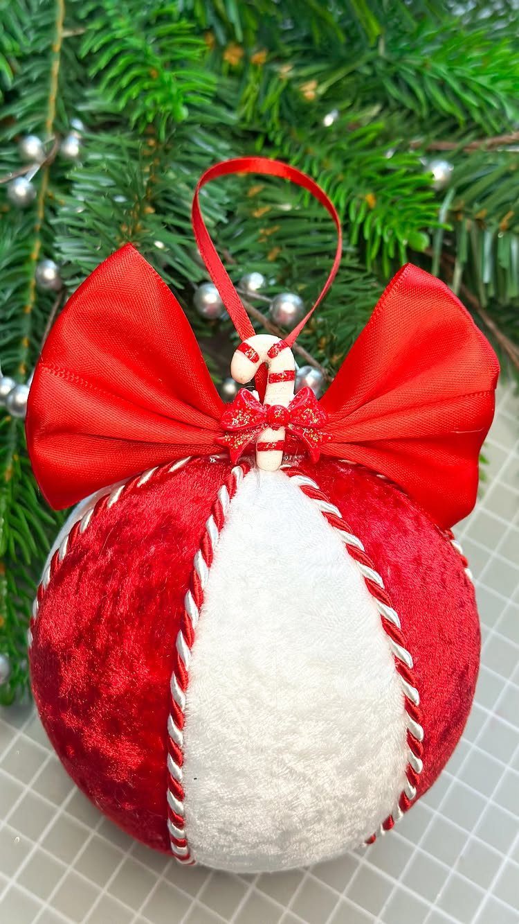 Red and white velvet Christmas ornament with a large red bow and small candy cane.