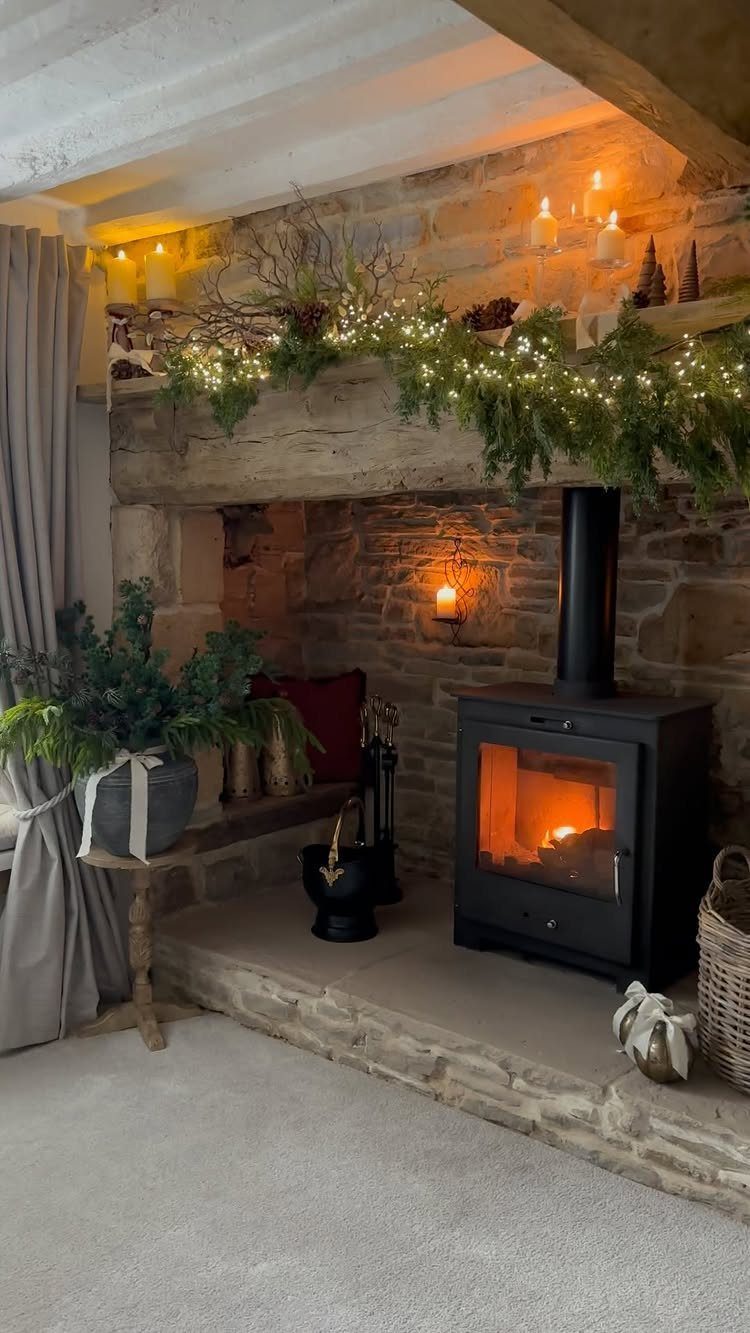 Evergreen garland with fairy lights draped across a rustic stone fireplace mantel.