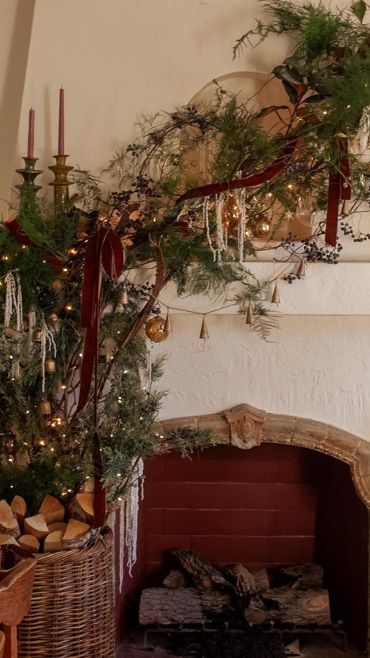 Evergreen garland with red ribbons and fairy lights draped over a white fireplace mantel.