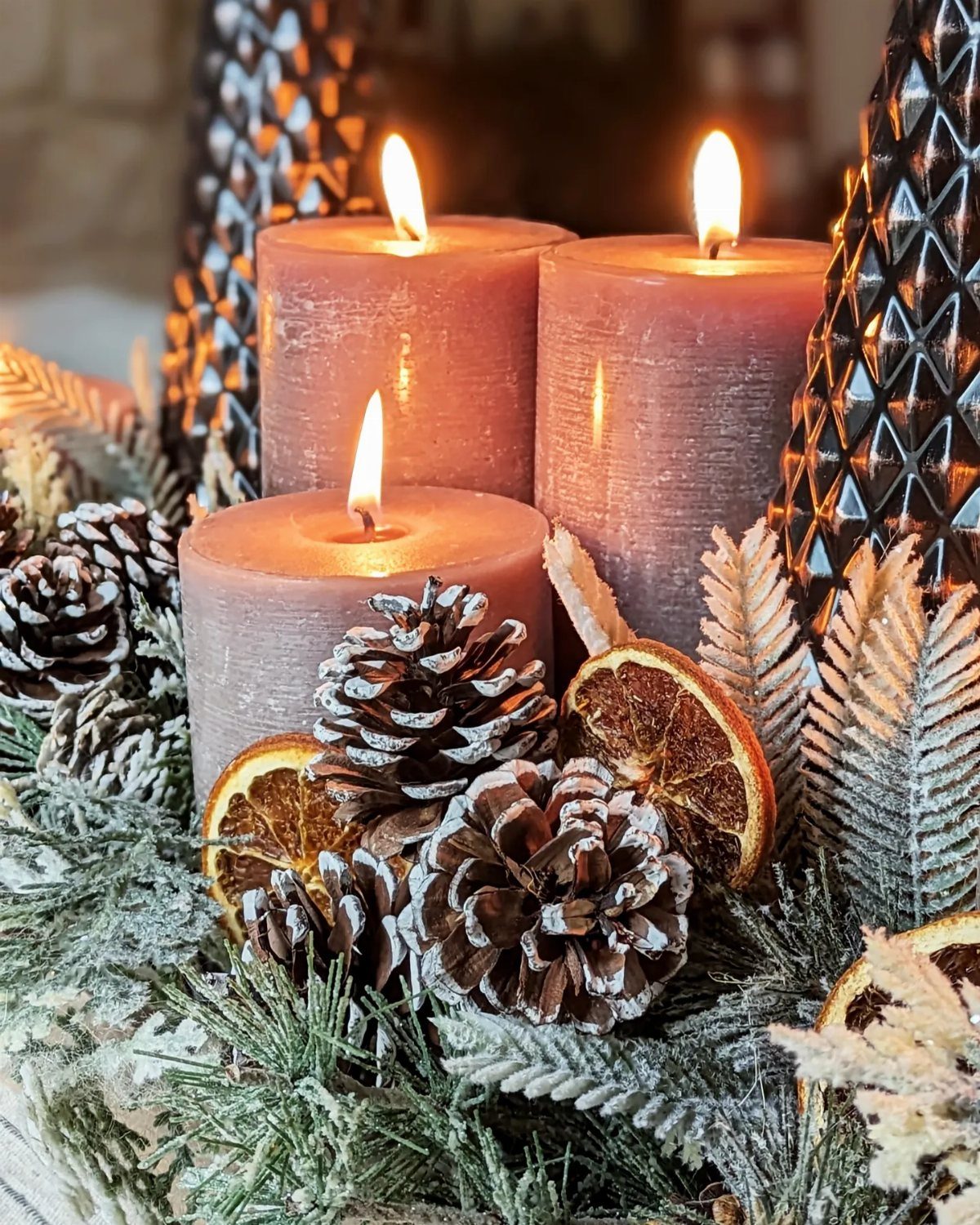 Christmas Table Centerpieces: 8 Ideas for Holiday Tables 8 Three lit pillar candles surrounded by pinecones, dried orange slices, and evergreen branches on a table.