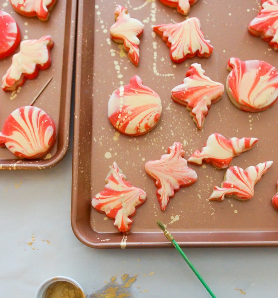 Red and white marbled icing decorated sugar cookies on brown baking sheets.