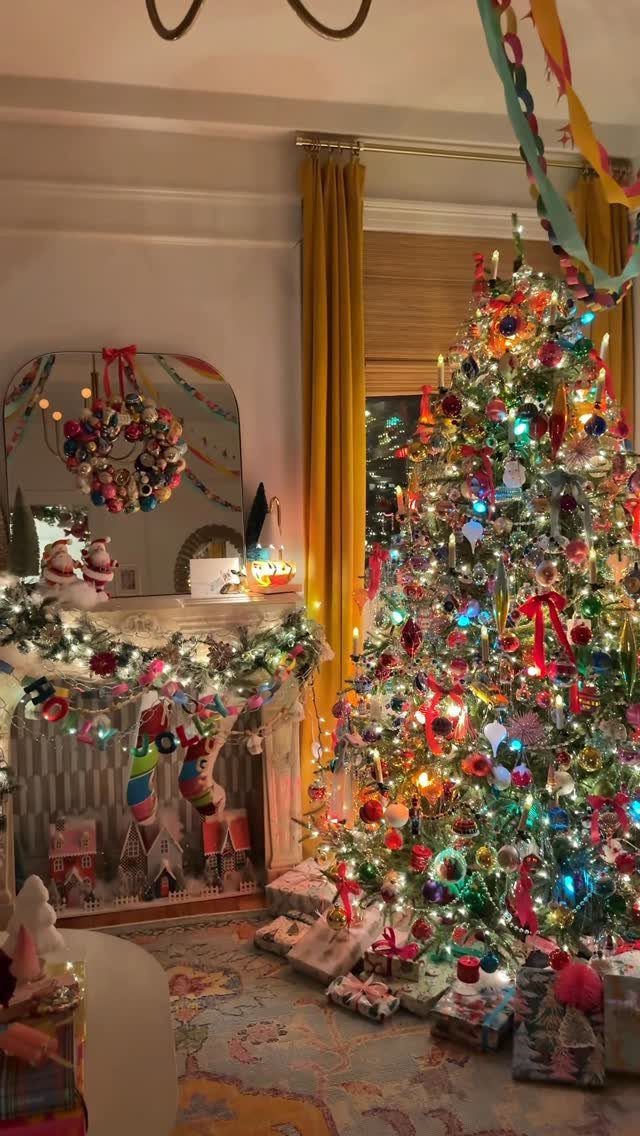 A decorated Christmas tree with colorful ornaments and bows standing next to a festive fireplace.