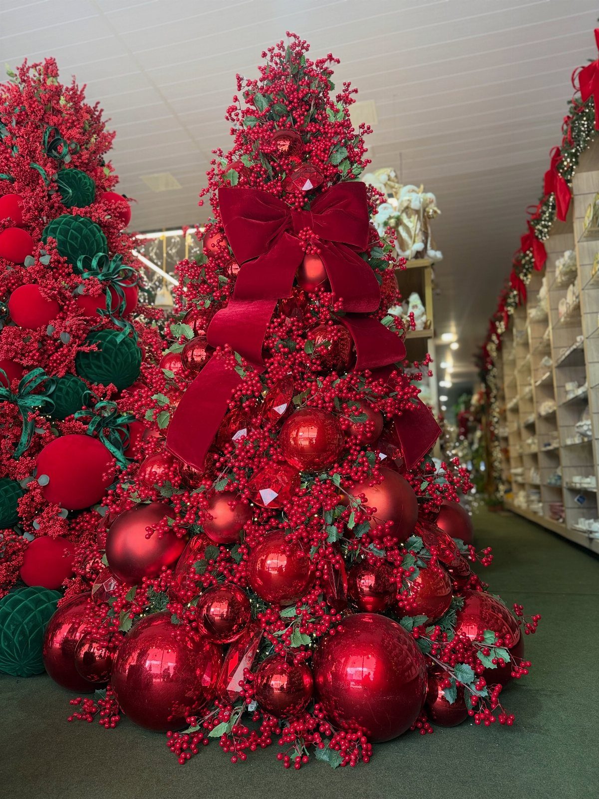 A Christmas tree covered in red berries, red ornaments, and a large red velvet bow.