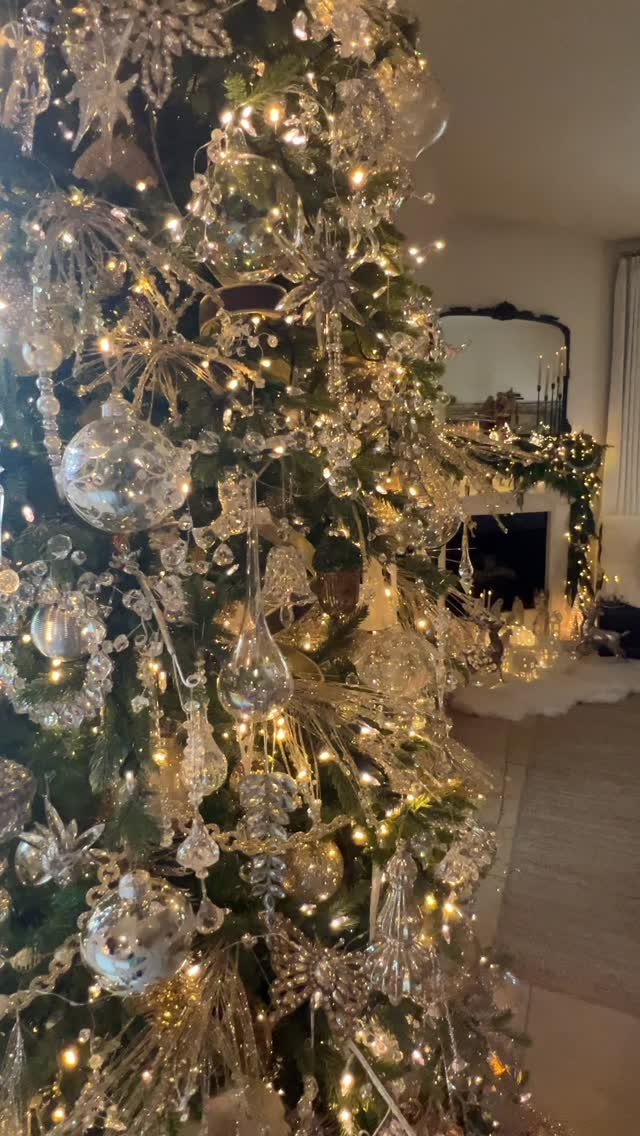 Silver glittery ornaments and sparkling baubles hanging on a lit Christmas tree.