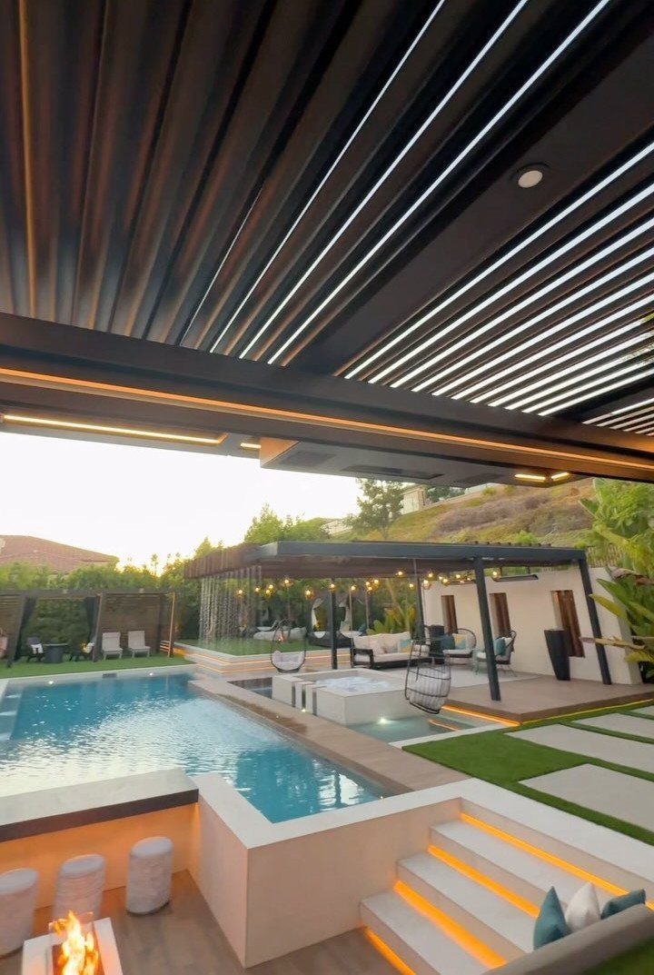 Modern louvered pergola overlooking a luxury swimming pool and outdoor lounge area.
