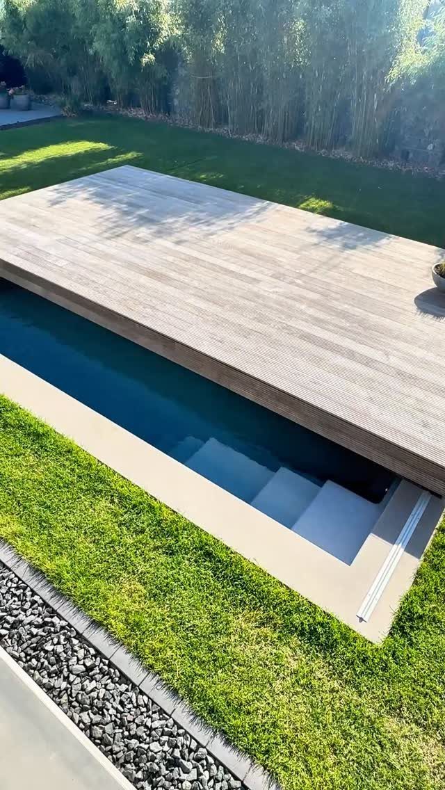A modern swimming pool with a large wooden deck structure partially covering the water surface.