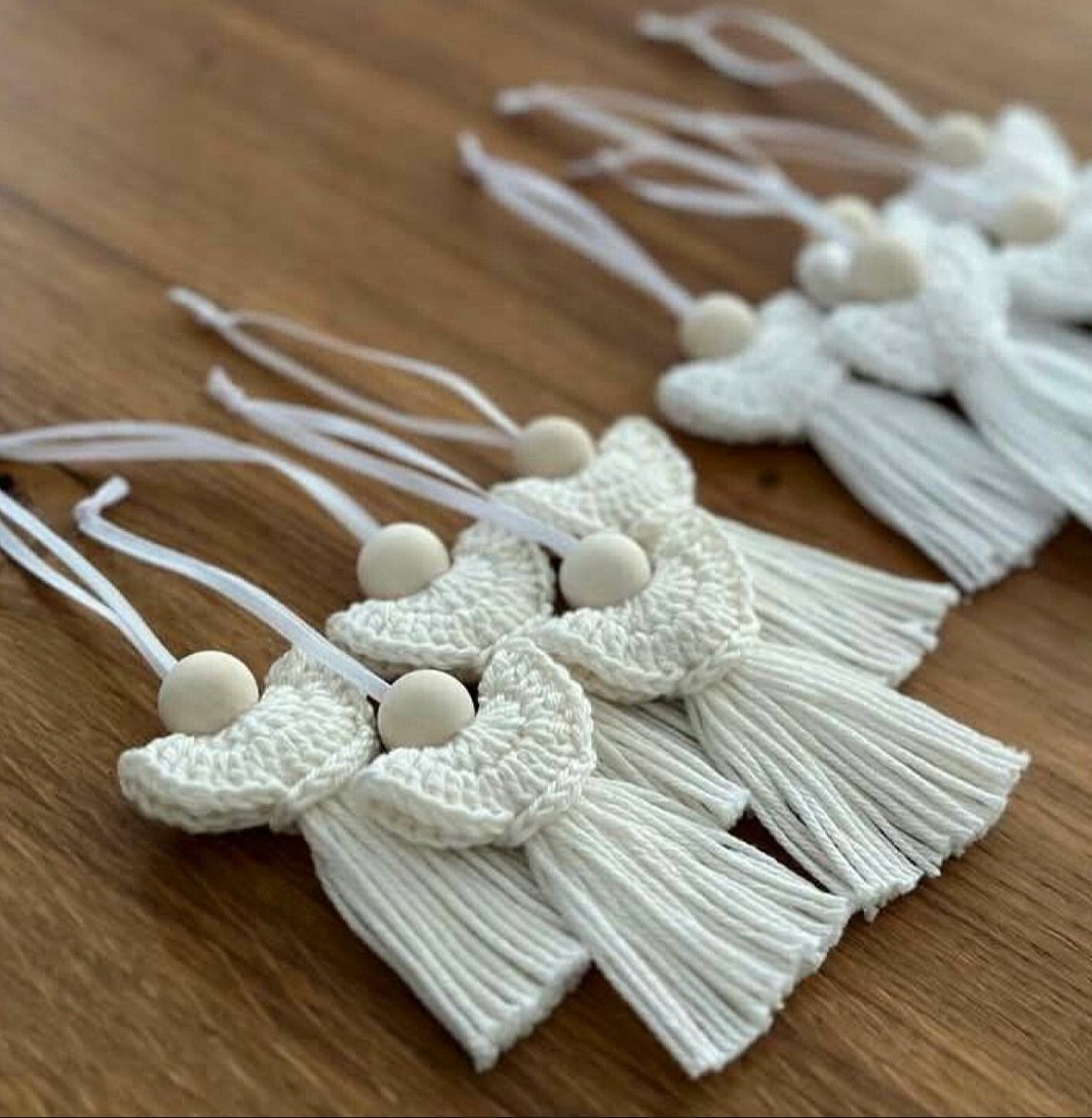 Crochet Christmas Ornaments: 19 Free Patterns for 2026 19 White crochet ornaments with tassels and wooden beads resting on a wooden table surface.