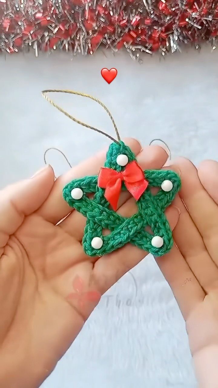 Crochet Christmas Ornaments: 19 Free Patterns for 2026 3 Hands holding a green crocheted star ornament with a red bow and white beads.