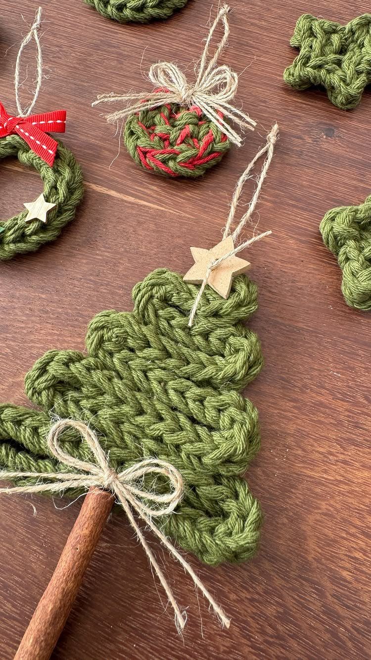 Green crocheted Christmas tree ornaments with wooden stars and twine bows on a wooden surface.