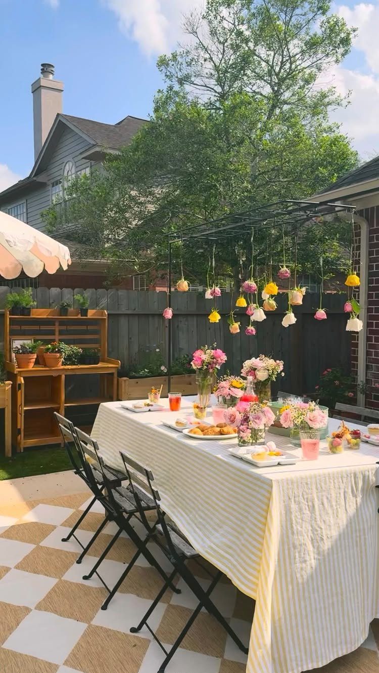 Decorating a Patio: 10 Ideas for a Space You Actually Use 6 A decorated outdoor dining table with pink flowers and hanging floral ornaments on a patio.