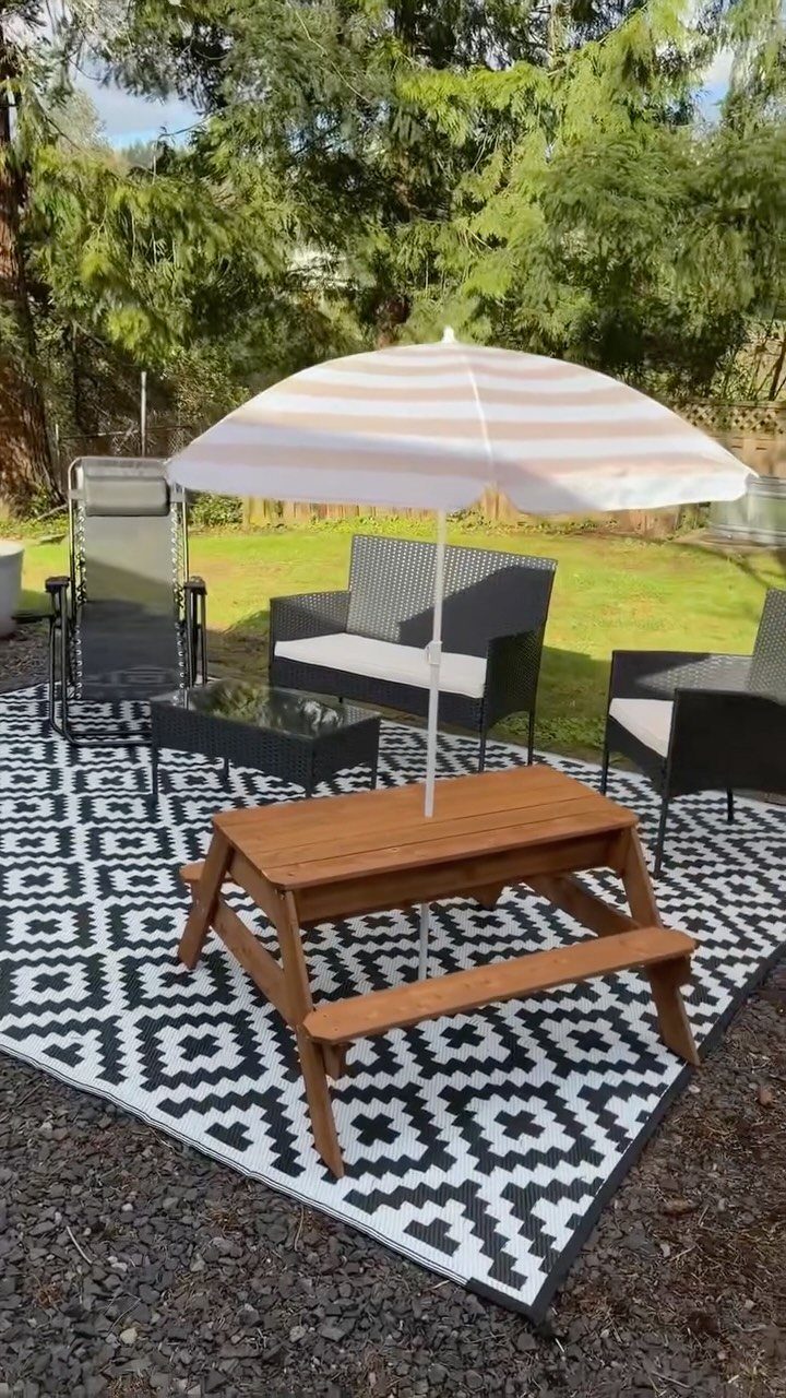 Decorating a Patio: 10 Ideas for a Space You Actually Use 4 Black and white geometric patterned outdoor rug under patio furniture and a wooden picnic table.