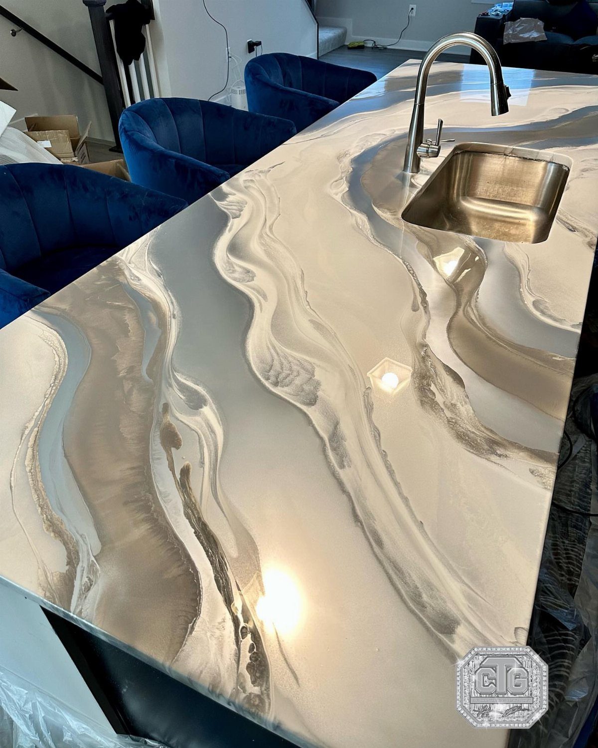 6 DIY Kitchen Countertops That Cost Less Than You Expect 3 A glossy kitchen countertop with swirling grey and white marble-like epoxy patterns and a sink.