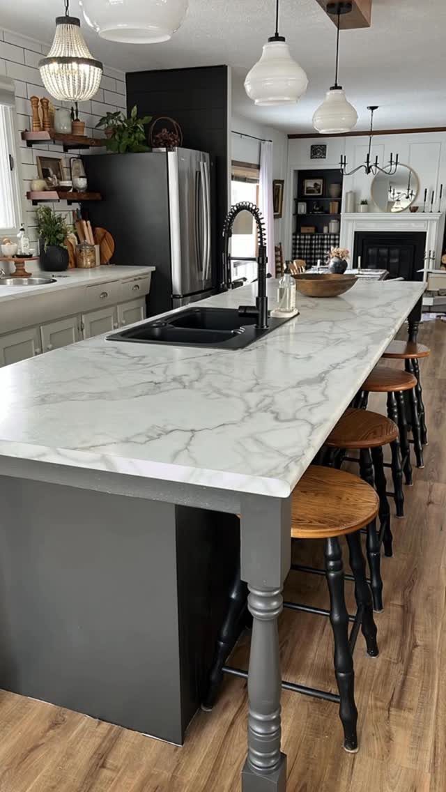 6 DIY Kitchen Countertops That Cost Less Than You Expect 4 White marble-patterned kitchen island countertop with wooden stools in a modern kitchen setting.