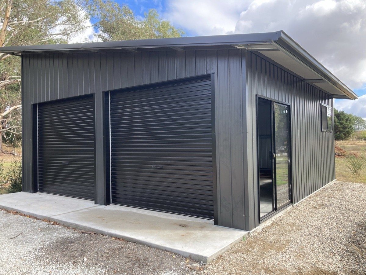 DIY Modern Shed: 19 Plans for Every Yard and Budget 2 A modern black metal shed featuring two roll-up doors and a glass sliding door.