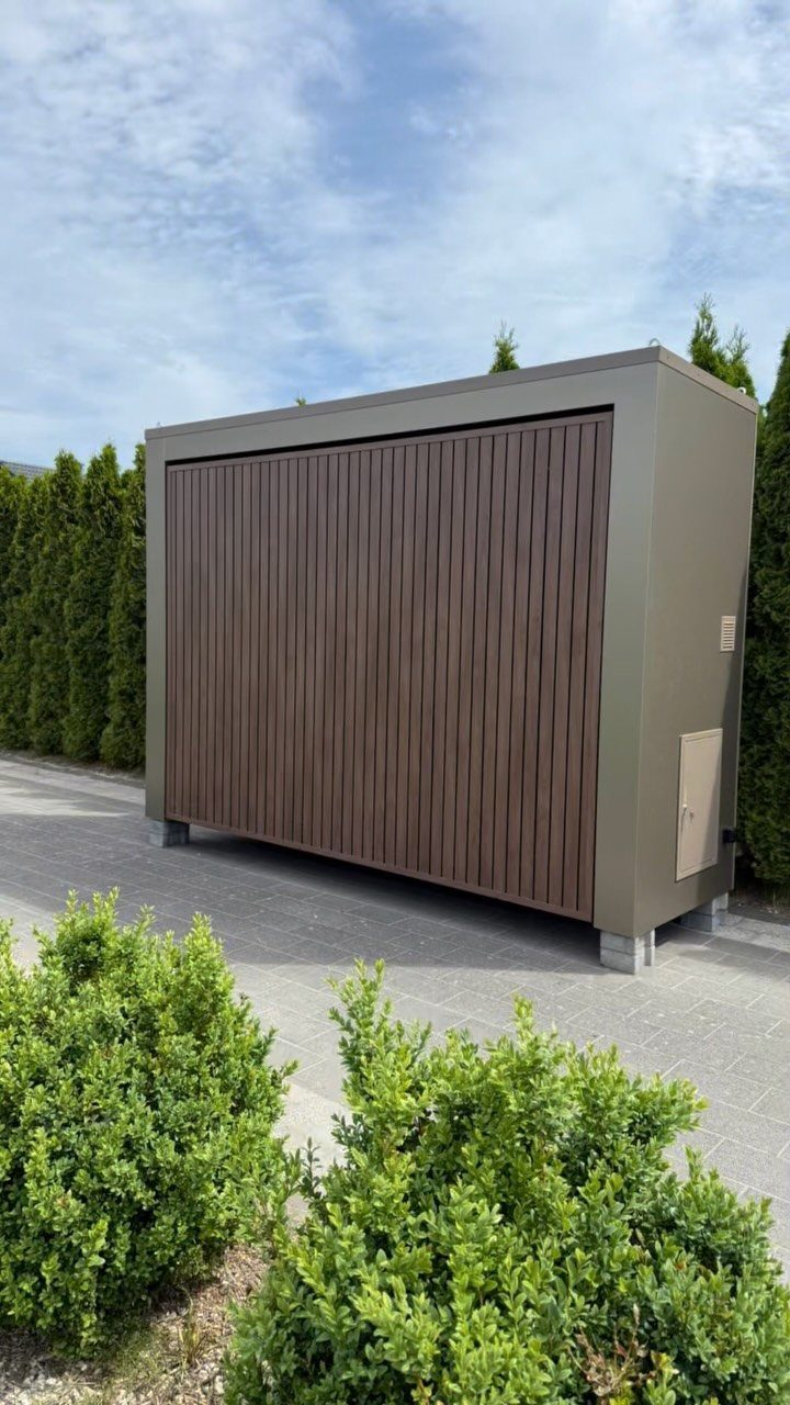 DIY Modern Shed: 19 Plans for Every Yard and Budget 3 Modern storage shed with brown wood slats and olive green metal siding sitting on pavement.