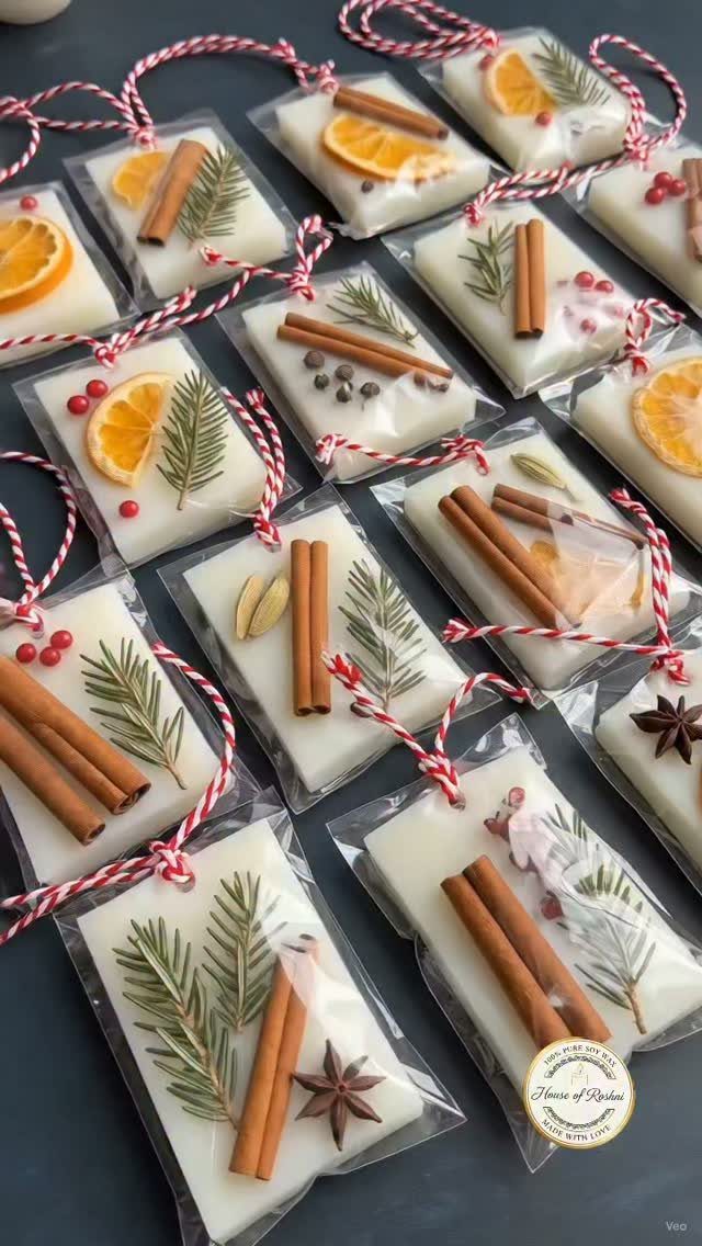 Rectangular white wax ornaments decorated with cinnamon sticks, star anise, and greenery, wrapped in clear plastic.