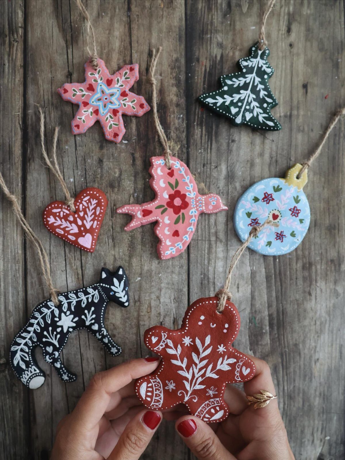 Hand-painted salt dough ornaments in various shapes resting on a rustic wooden background.