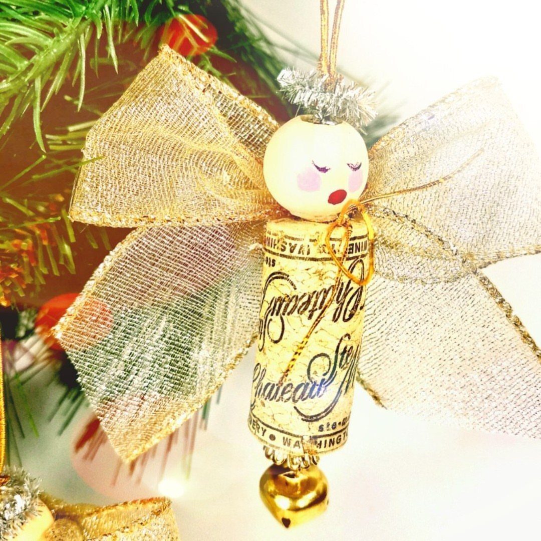 A handmade angel ornament made from a wine cork and wooden bead hanging on a tree.