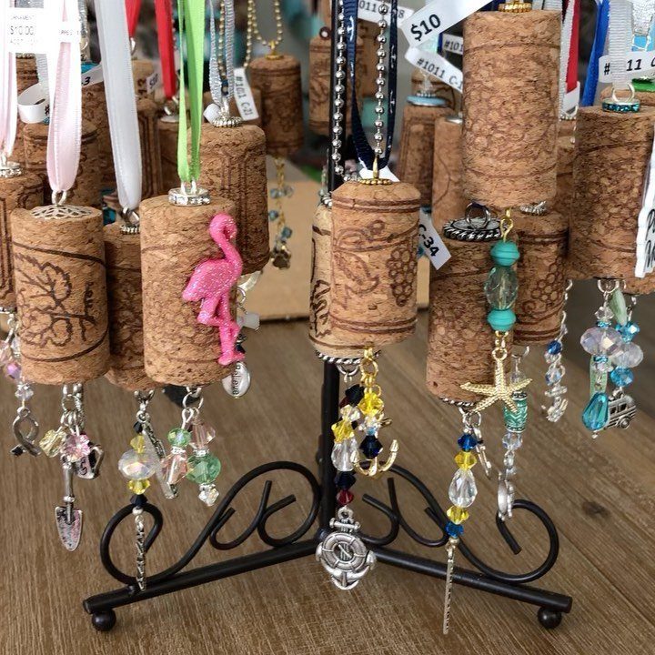 Wine cork ornaments decorated with various colorful beads and metal charms hanging from a black stand.