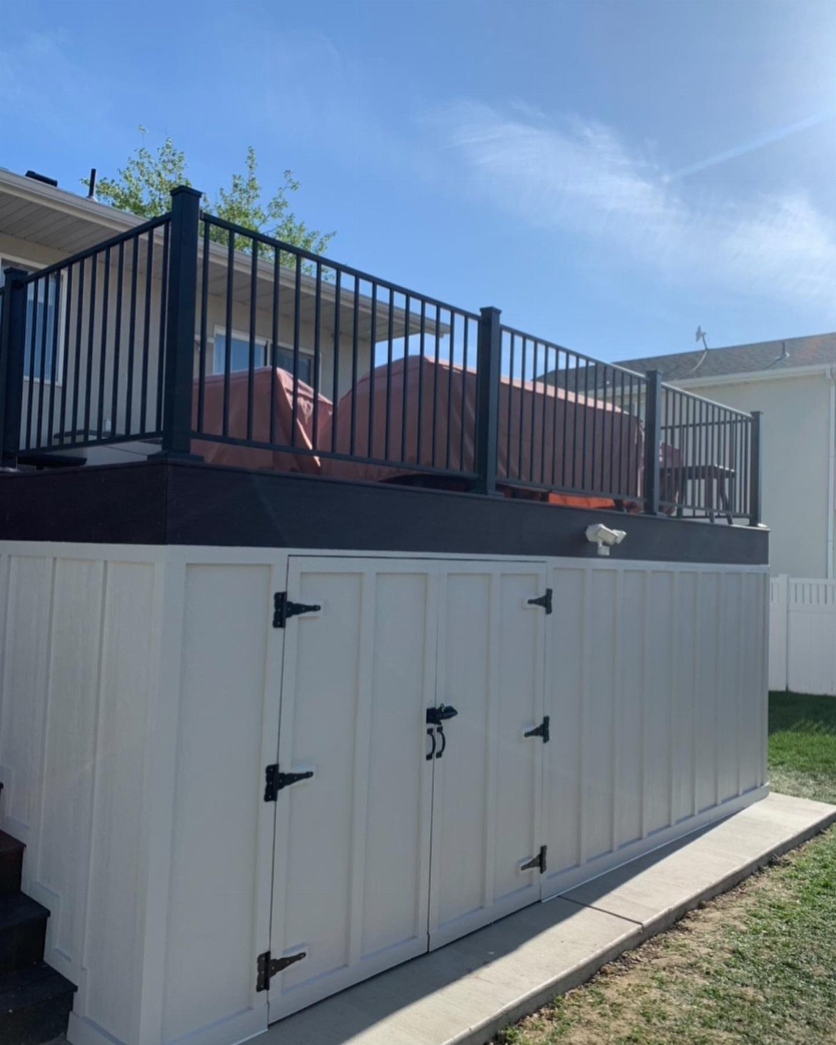 11 Elevated Deck Ideas: Multi-Level Looks, Storage & Rooftop Builds 2 White storage cabinets built into the space underneath an elevated wooden deck.