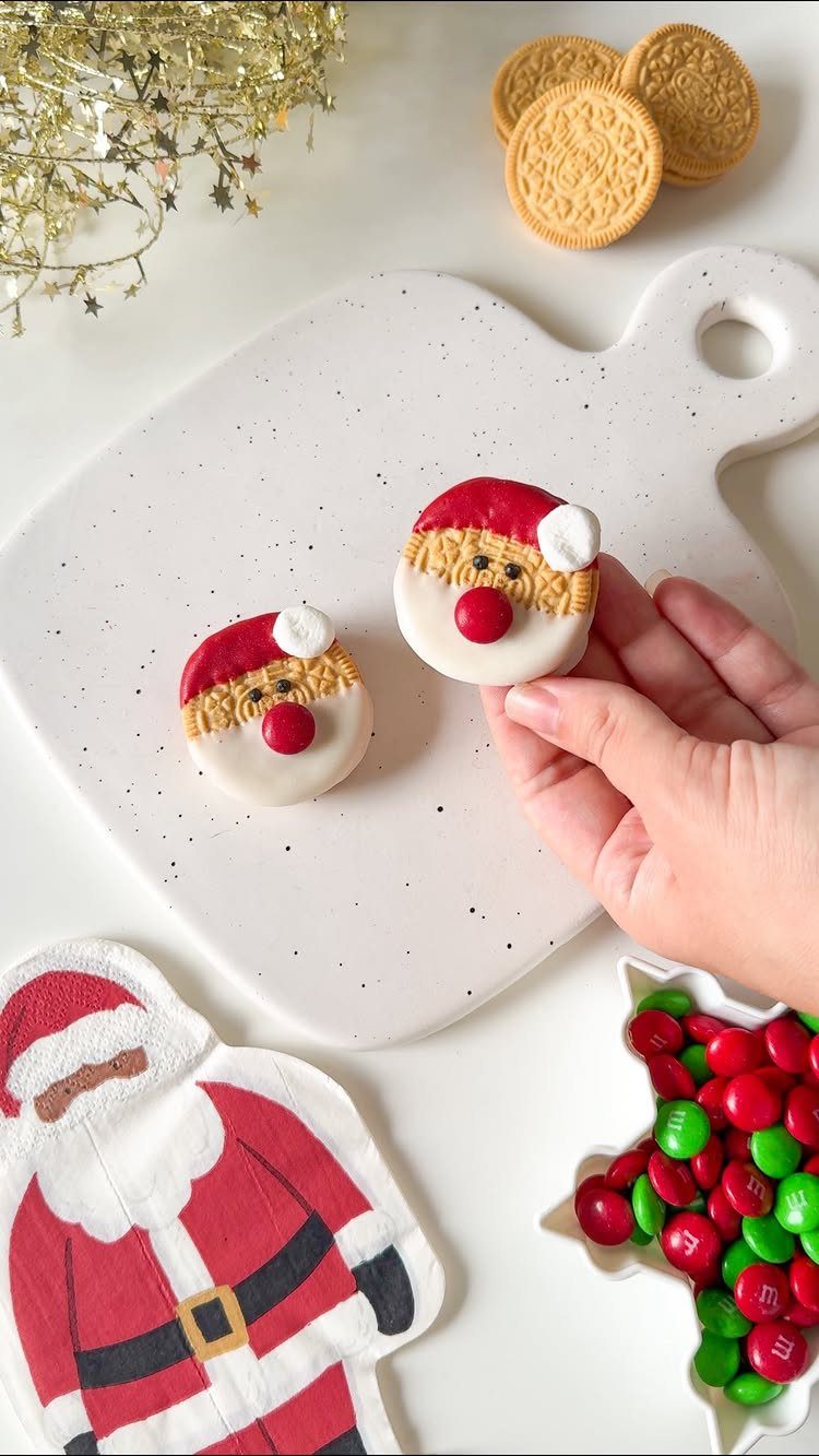 Fun Christmas Activities for Families: 18 Ideas With Photos 2 A hand holds a decorated Santa Claus cookie on a white speckled cutting board.