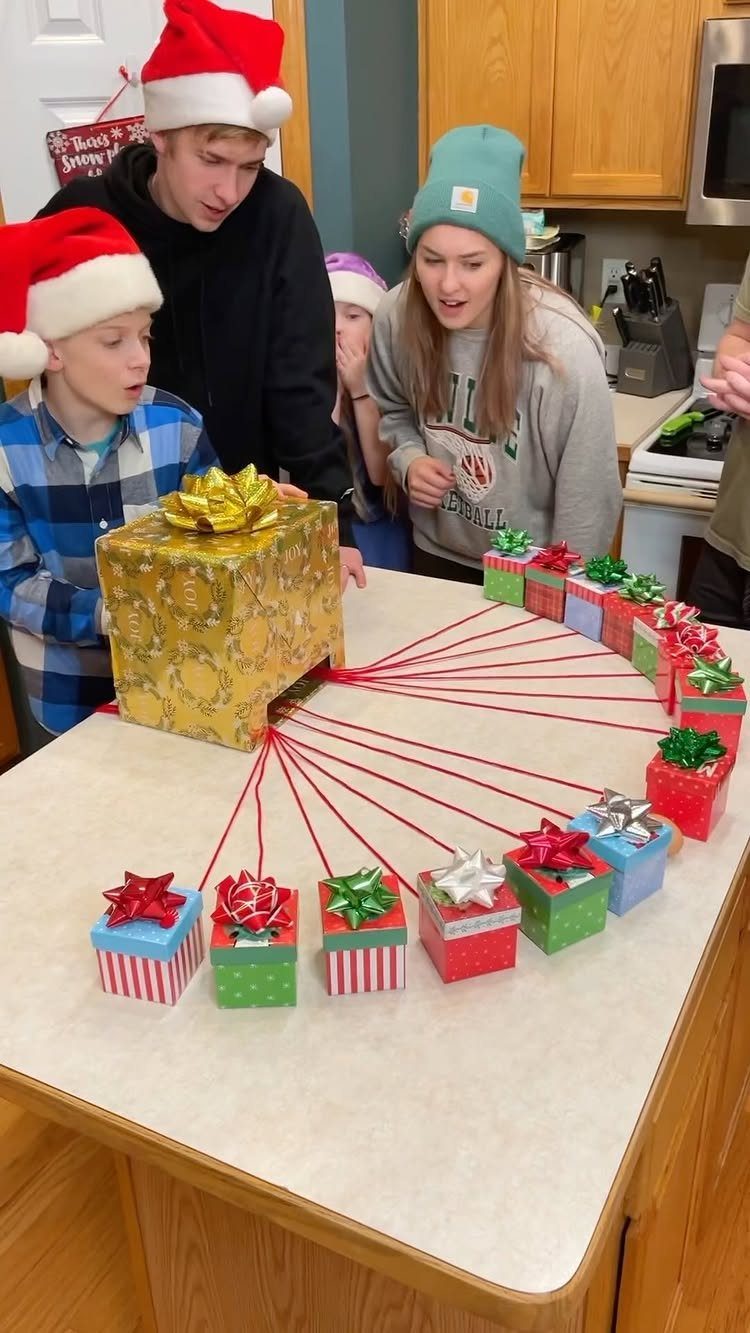 Fun Christmas Activities for Families: 18 Ideas With Photos 9 Children looking excitedly at a large gold gift box connected by red strings to smaller presents.