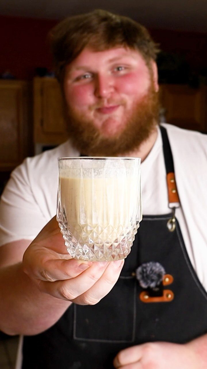 Fun Christmas Activities for Families: 18 Ideas With Photos 11 A bearded man in an apron holding a glass of creamy eggnog toward the camera.