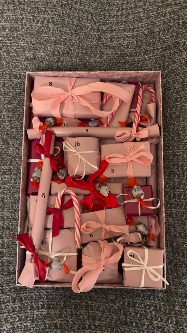 Small pink and red wrapped gift boxes with ribbons arranged inside a box.