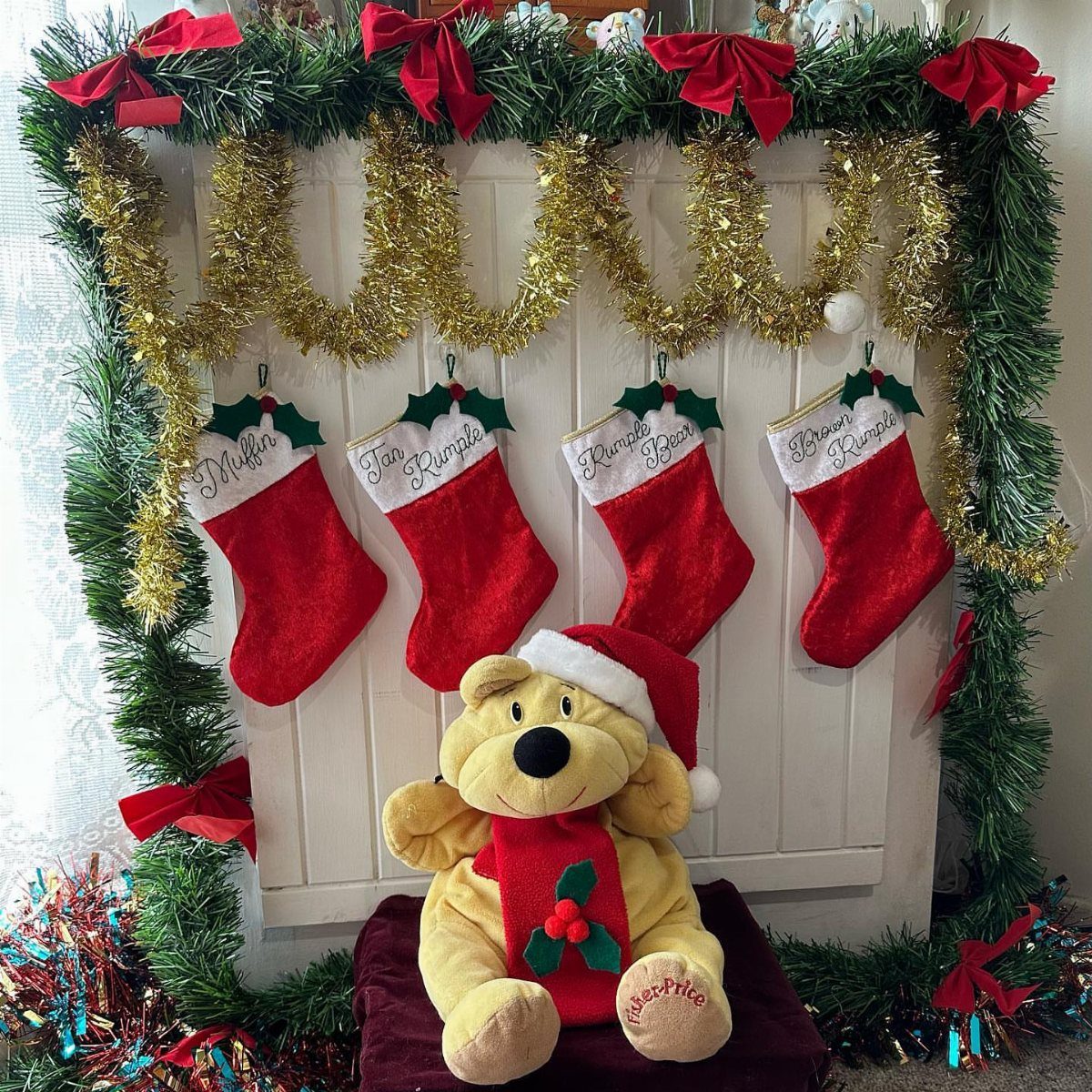 Four personalized red felt Christmas stockings hanging on a decorated white mantelpiece.
