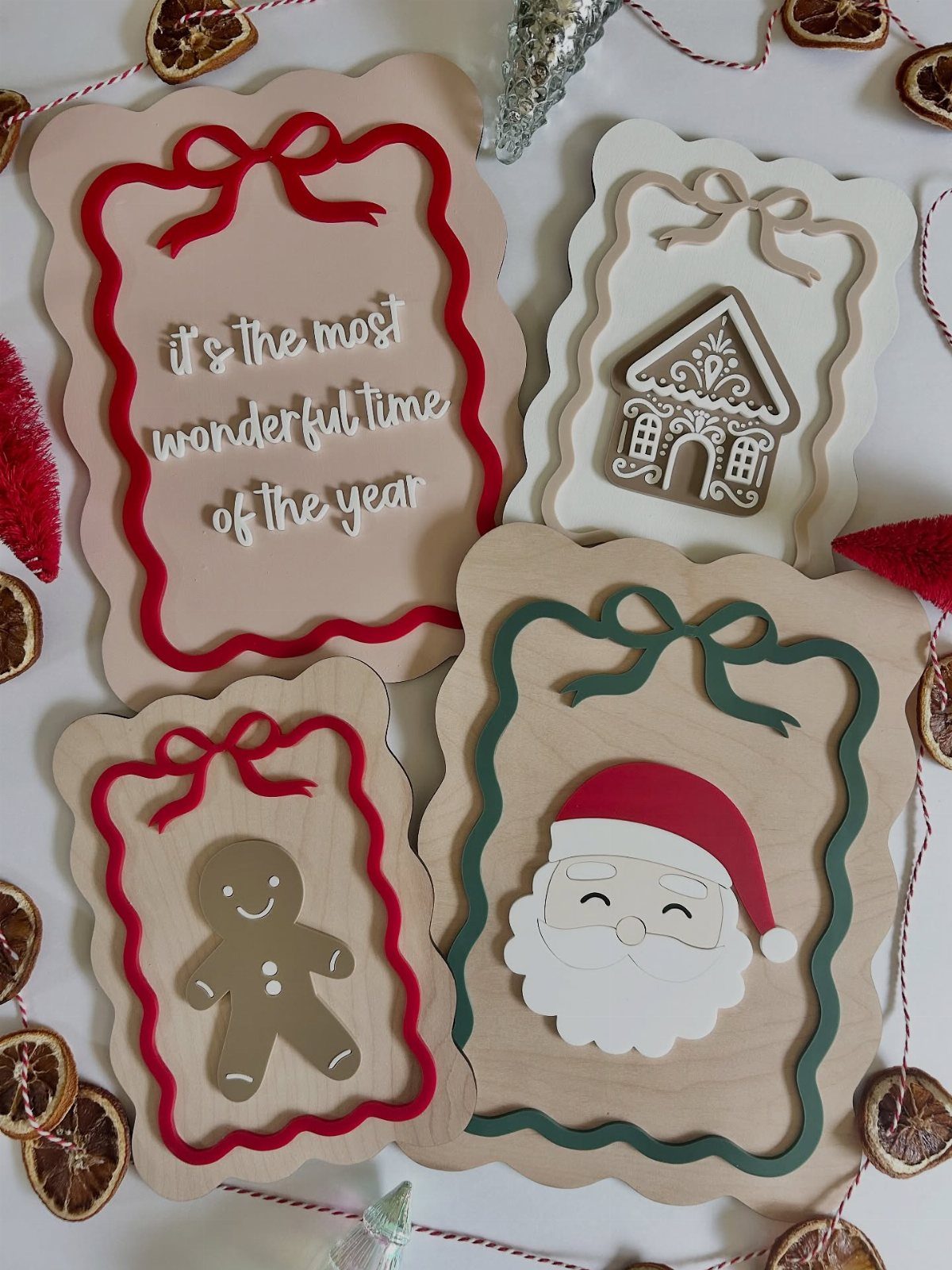 Four wooden scalloped holiday signs with festive characters and text on a white background.