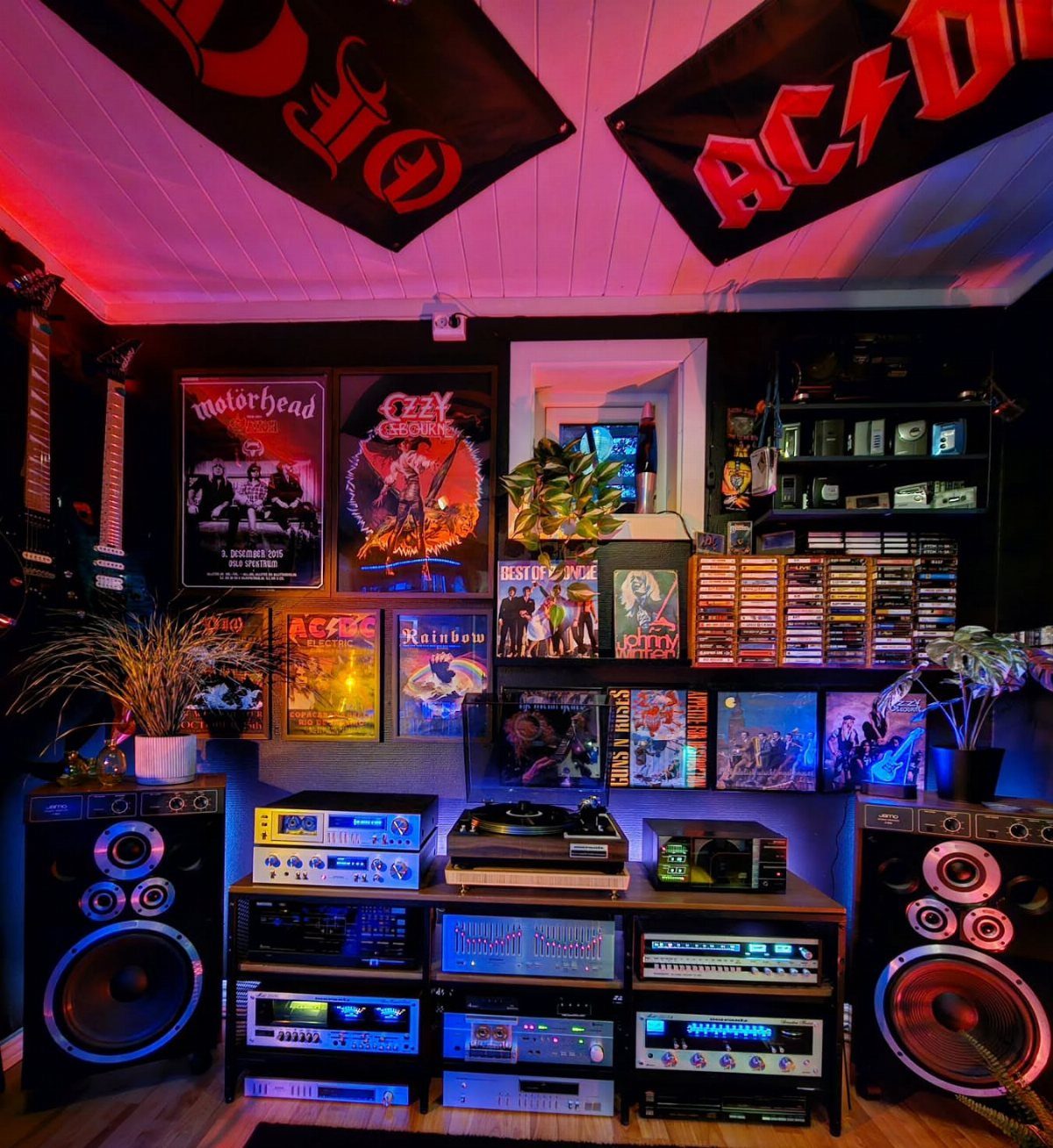 Vintage audio equipment with large speakers, amplifiers, and a turntable surrounded by rock music posters.