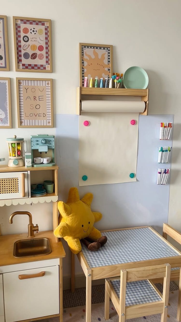 17 Garage Playroom Ideas for Safe, Creative Kid Space 9 A small wooden play table and kitchen set with art supplies and paper on the wall.