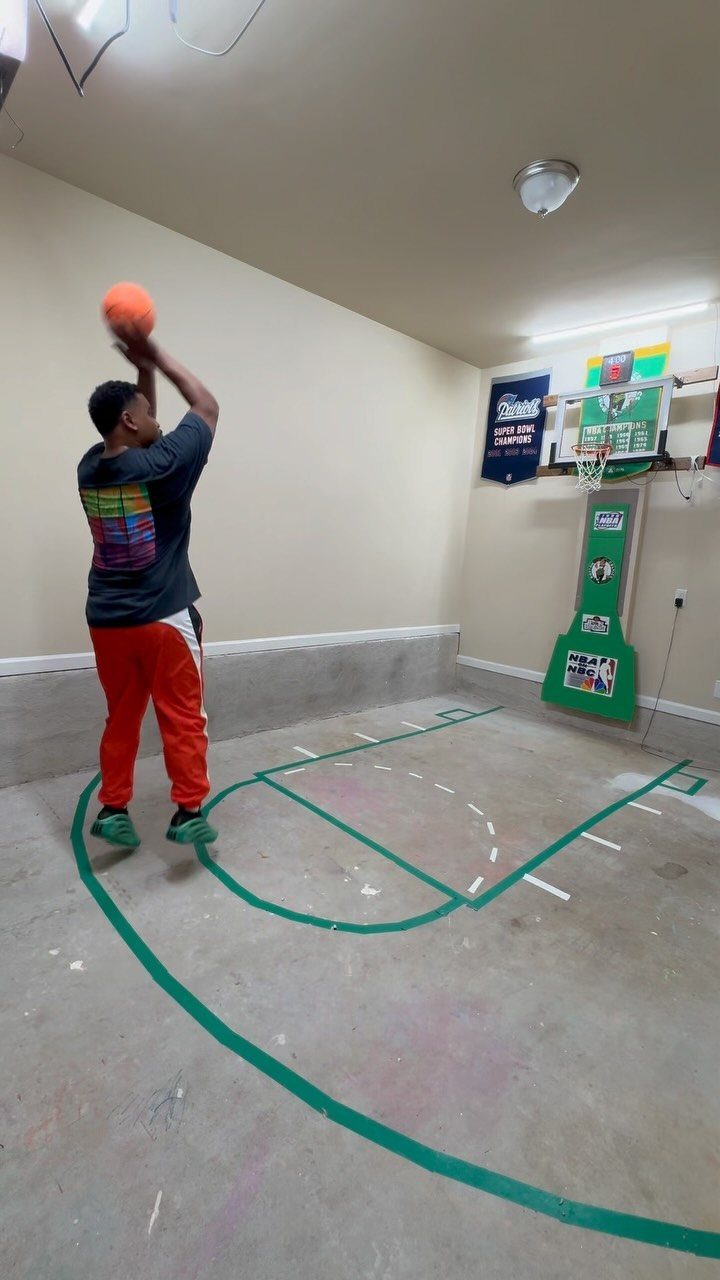 17 Garage Playroom Ideas for Safe, Creative Kid Space 14 Boy shooting an orange basketball toward a green hoop in a garage court.