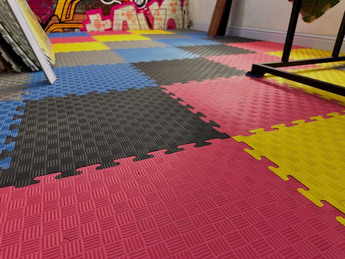 17 Garage Playroom Ideas for Safe, Creative Kid Space 1 Colorful interlocking foam floor mats in pink, yellow, blue, and grey cover the ground.