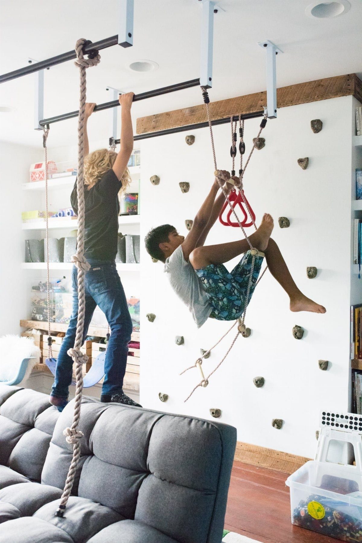 17 Garage Playroom Ideas for Safe, Creative Kid Space 5 Two children playing with indoor swings and climbing equipment in a bright playroom.