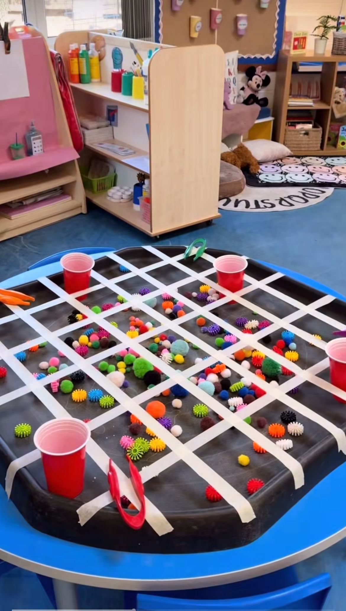17 Garage Playroom Ideas for Safe, Creative Kid Space 12 A sensory table filled with dark sand, colorful textured balls, and red plastic cups.
