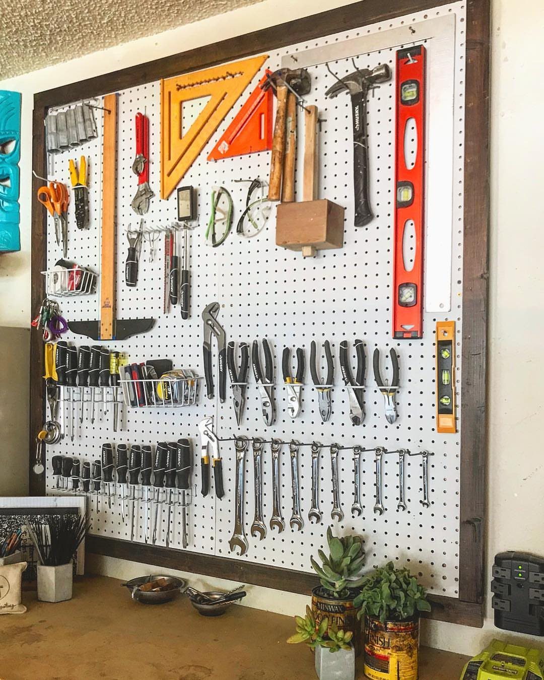 Garage Tool Setup: 8 Ideas That Actually Save Space and Time 4 Various hand tools organized on a white pegboard mounted within a dark wooden frame.