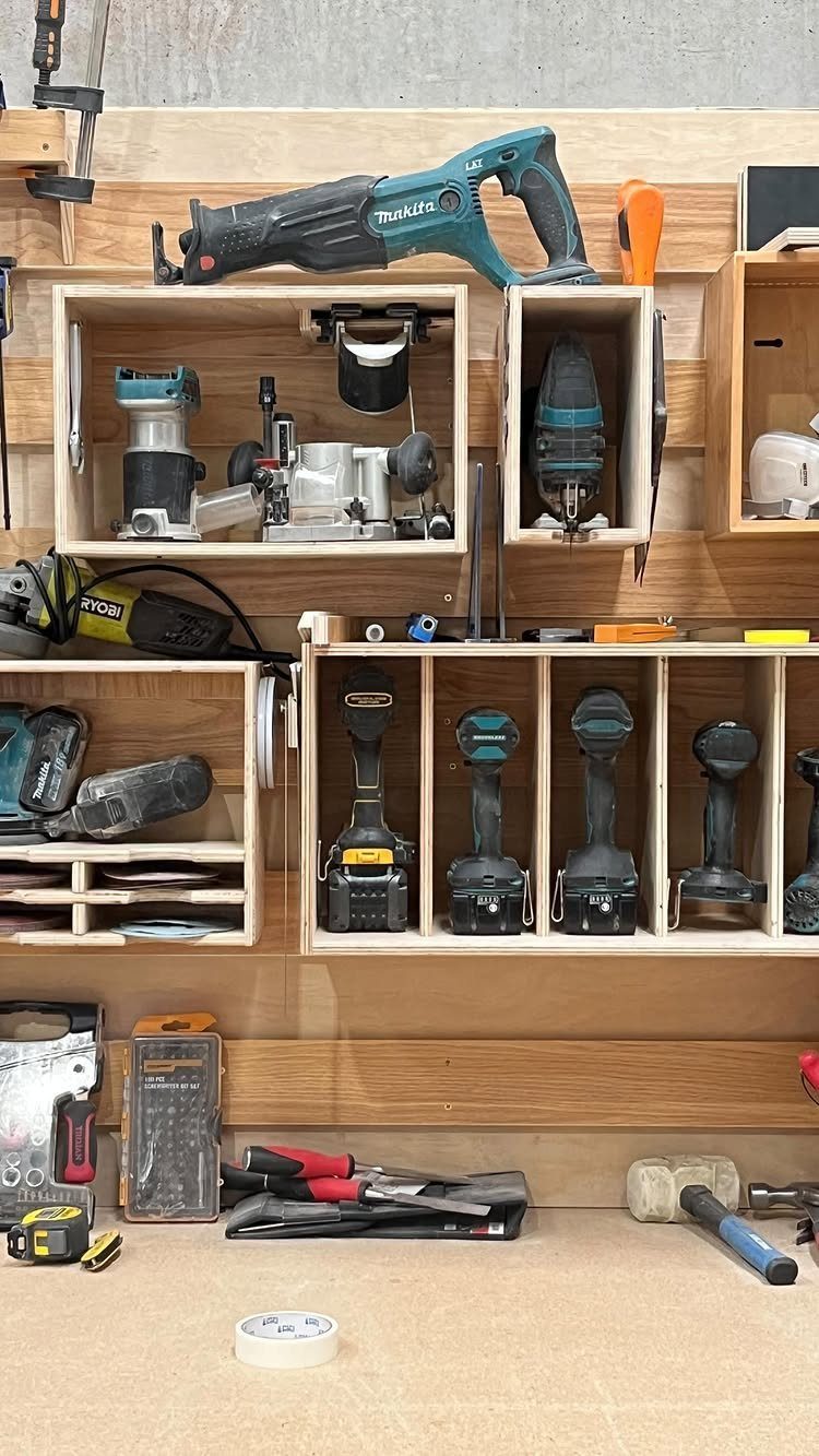 Garage Tool Setup: 8 Ideas That Actually Save Space and Time 6 Wooden tool organizer holding various power tools and hand tools on a workbench surface.